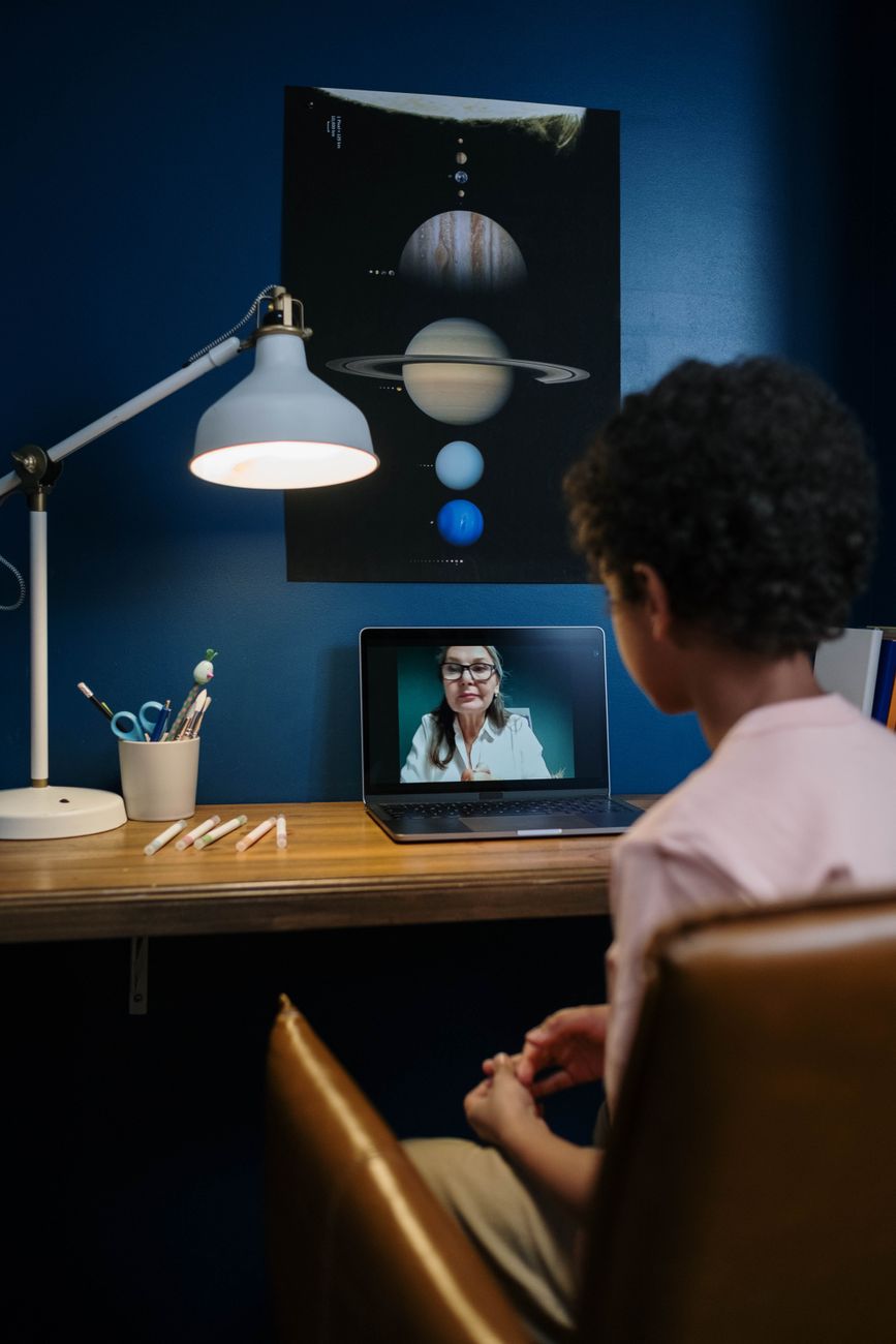 Child attending an online session with a therapist on a laptop at a desk