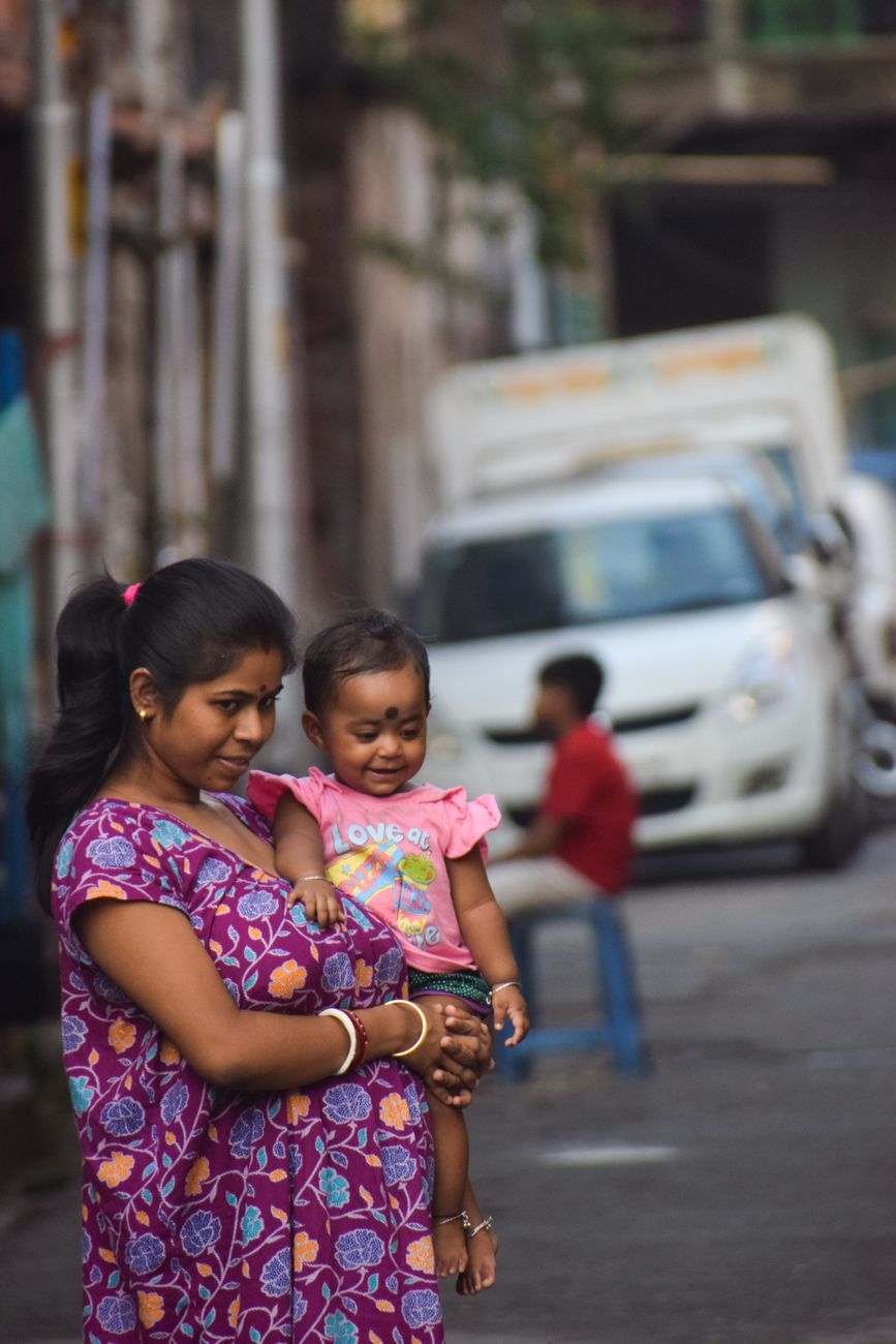 Indian mother holding her smiling toddler on a street